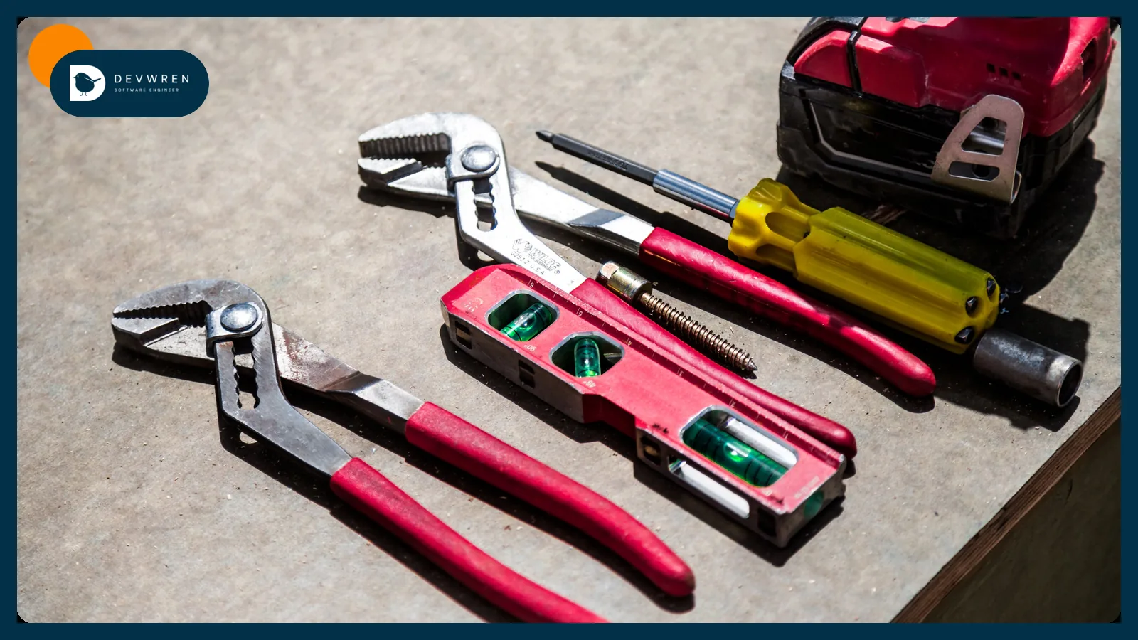 Pliers, screwdrivers, a level and a drill laid out on a workbench